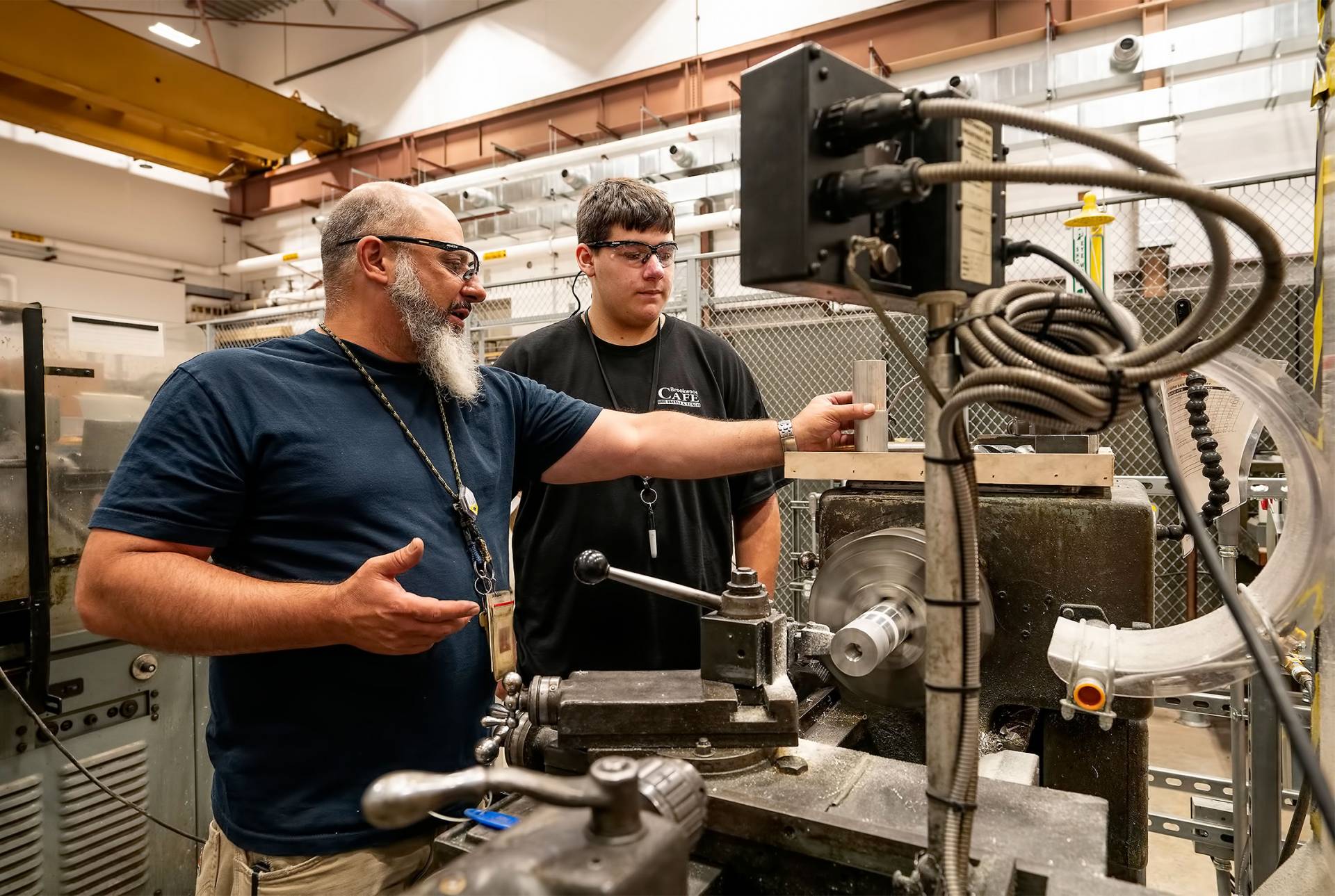 A technician points to a machine while next to a student