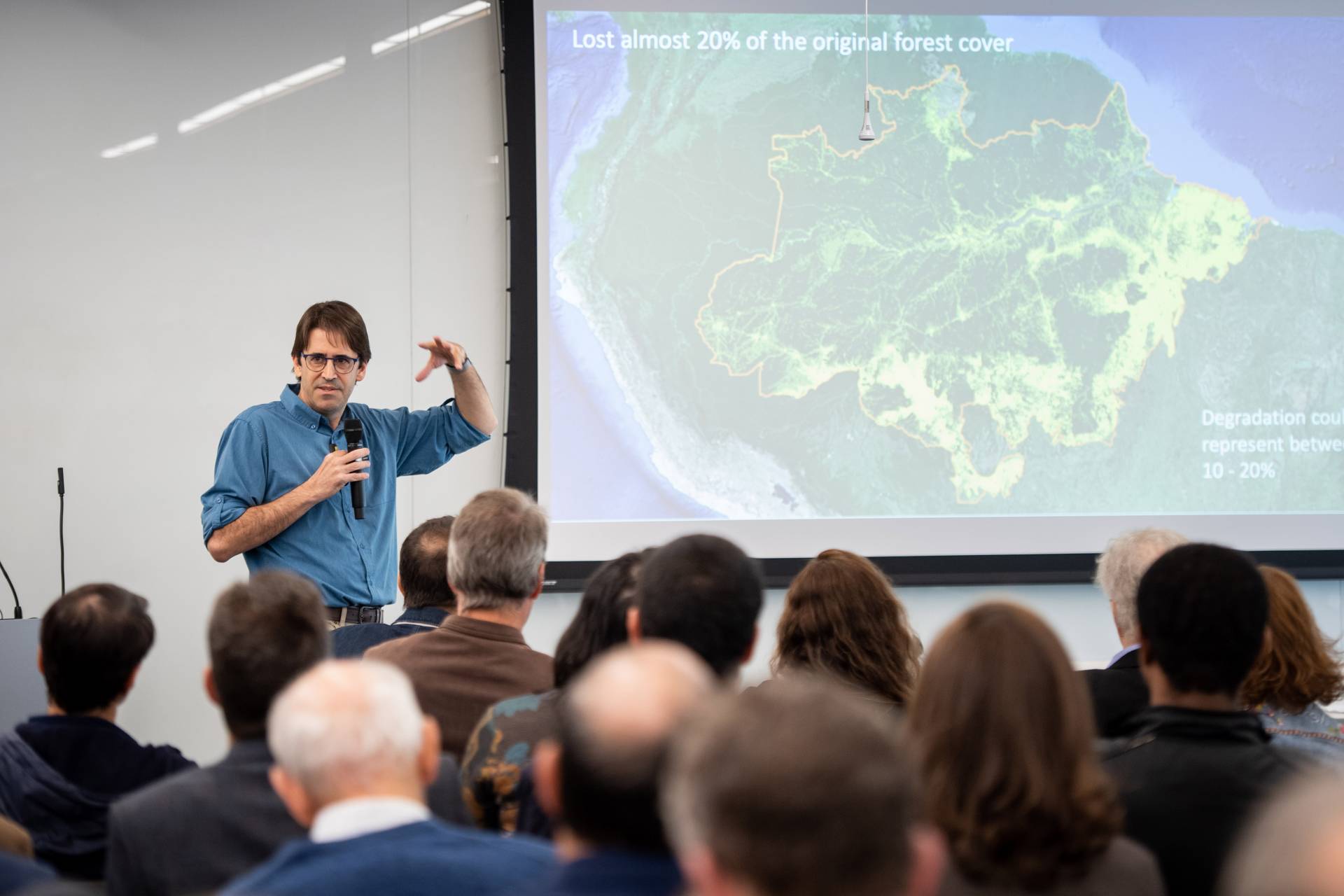 A man speaks in front of a projected map