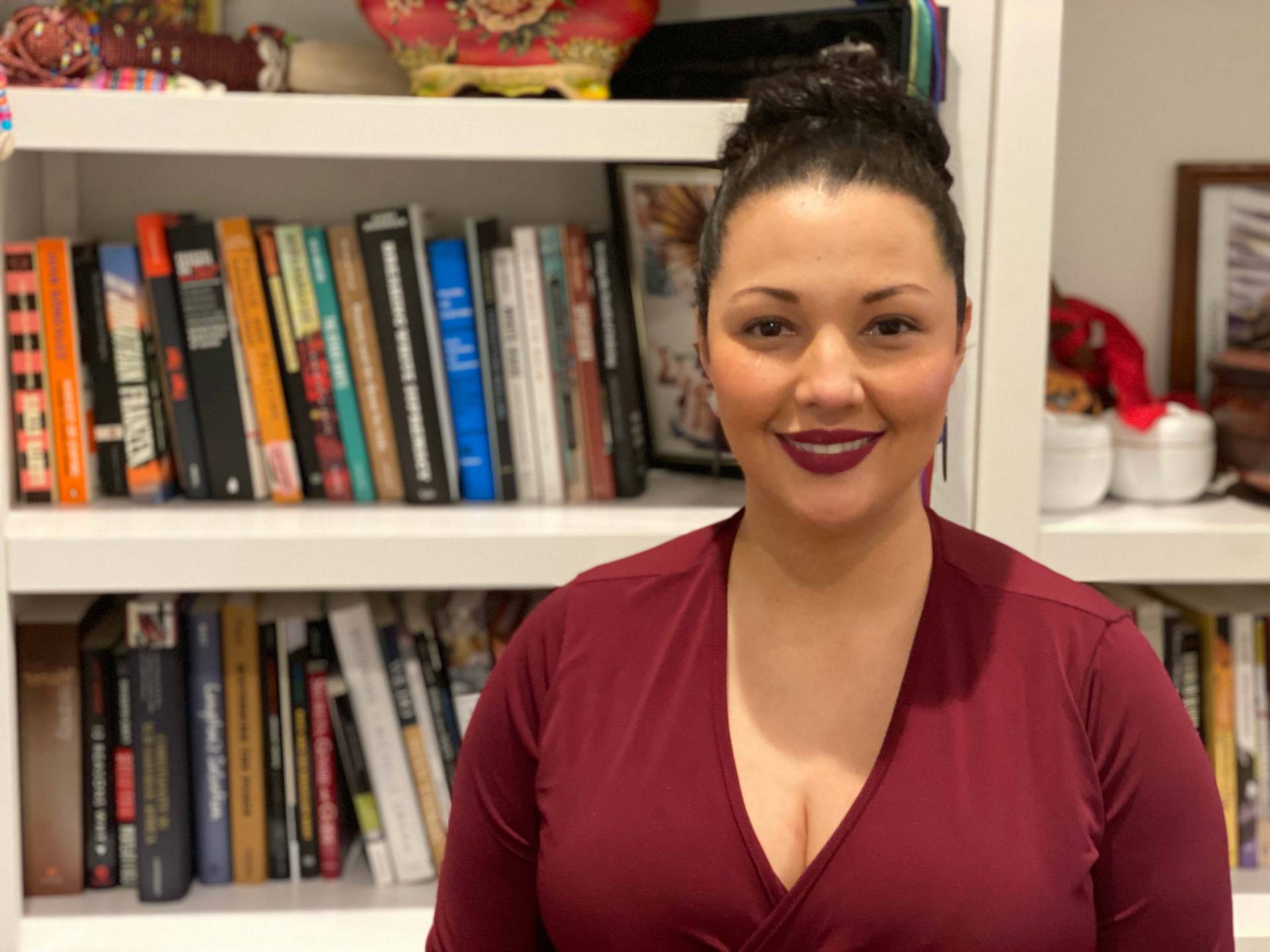 Aisha Beliso-De Jesús in front of her bookshelves