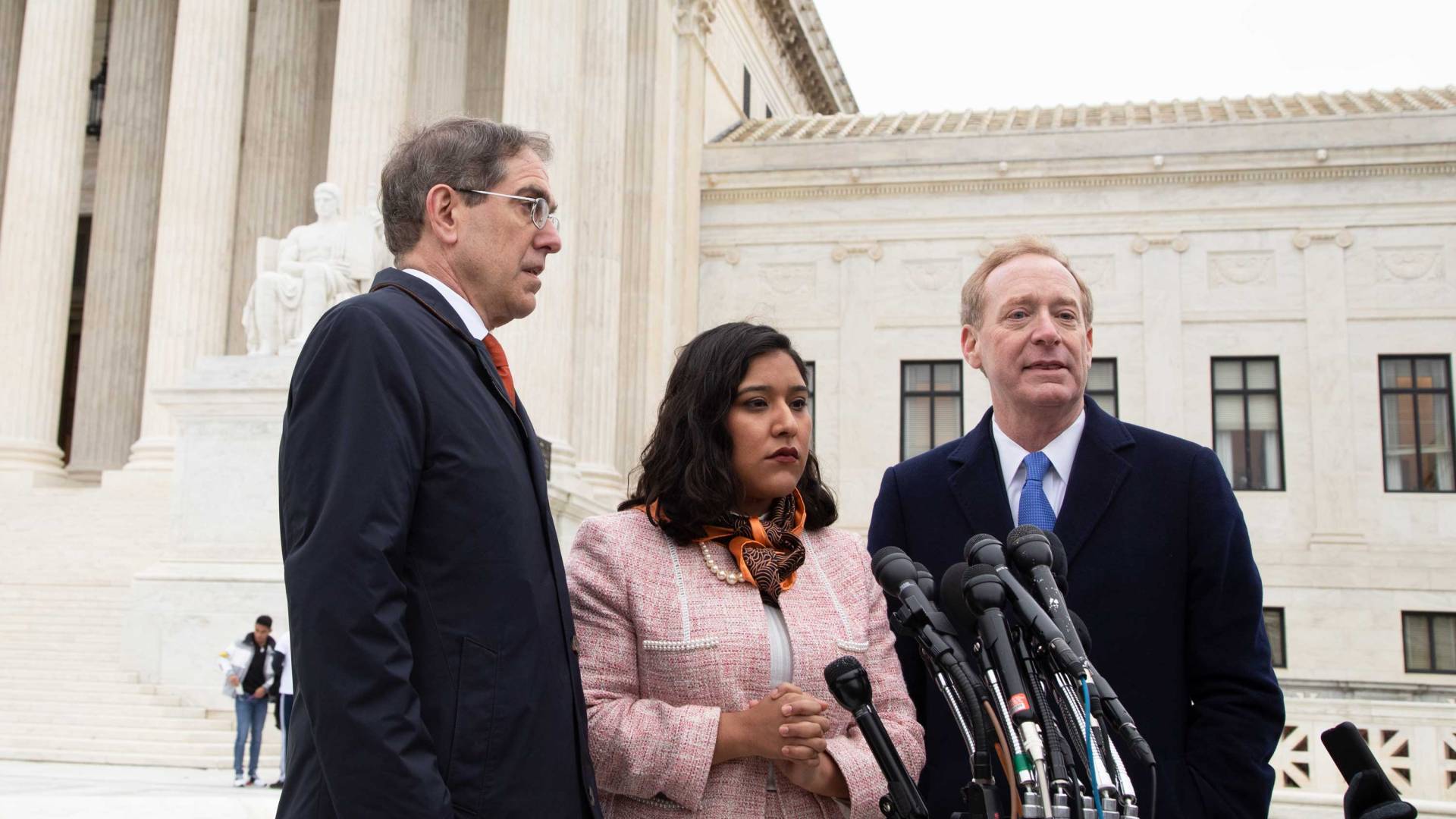 Christopher Eisgruber stands with Maria Perales Sanchez and Brad Smith on the hill to answer media questions
