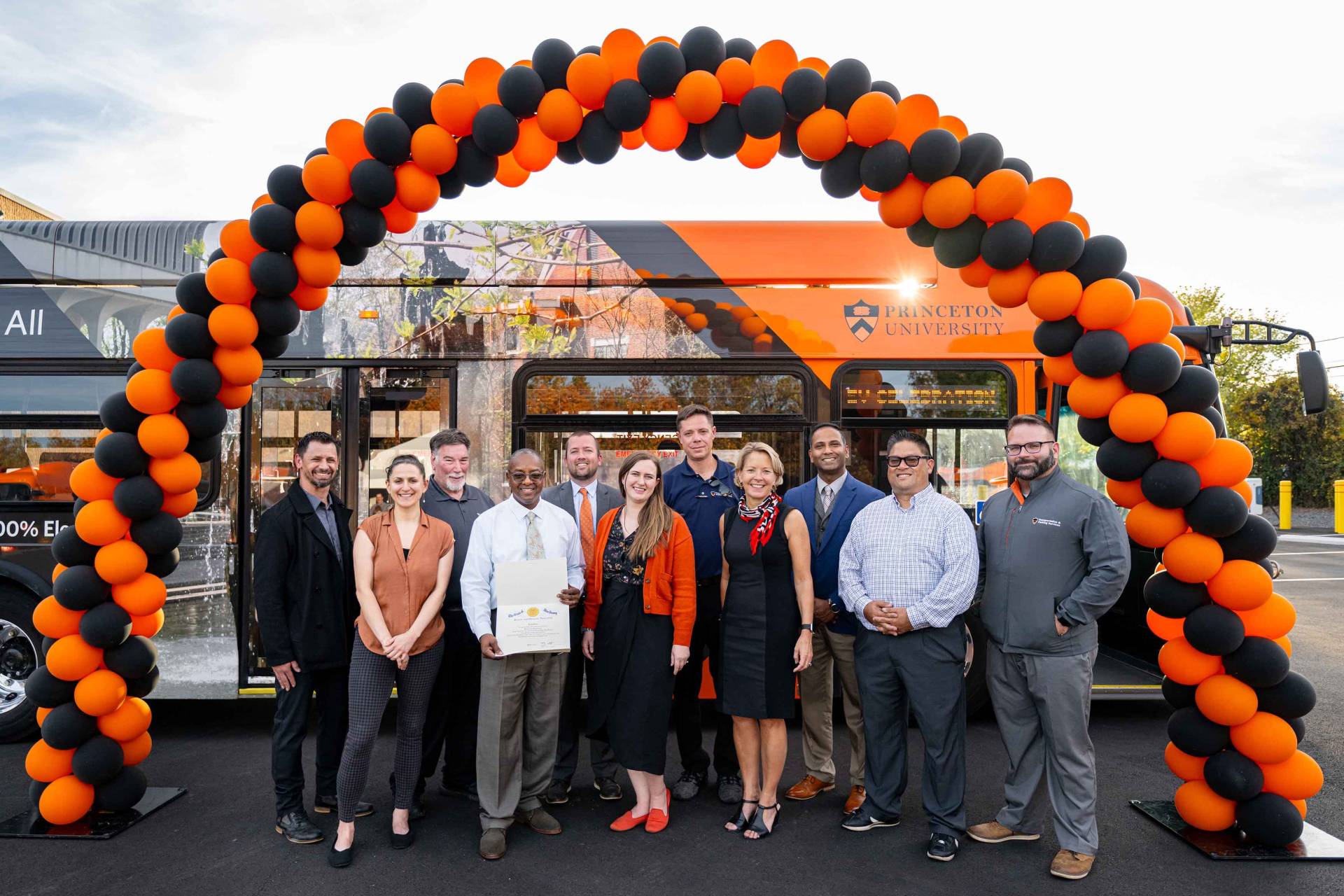 People in front of balloons and an electric bus