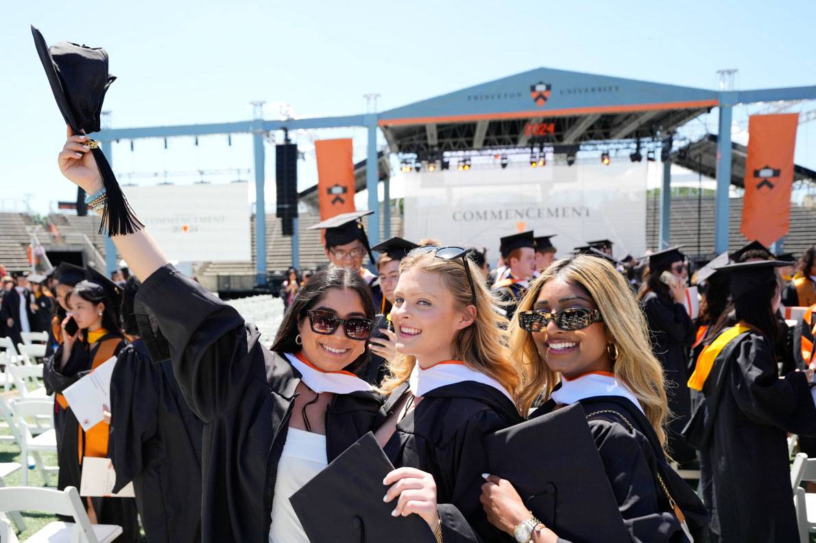 Students smiling, waving graduation hat