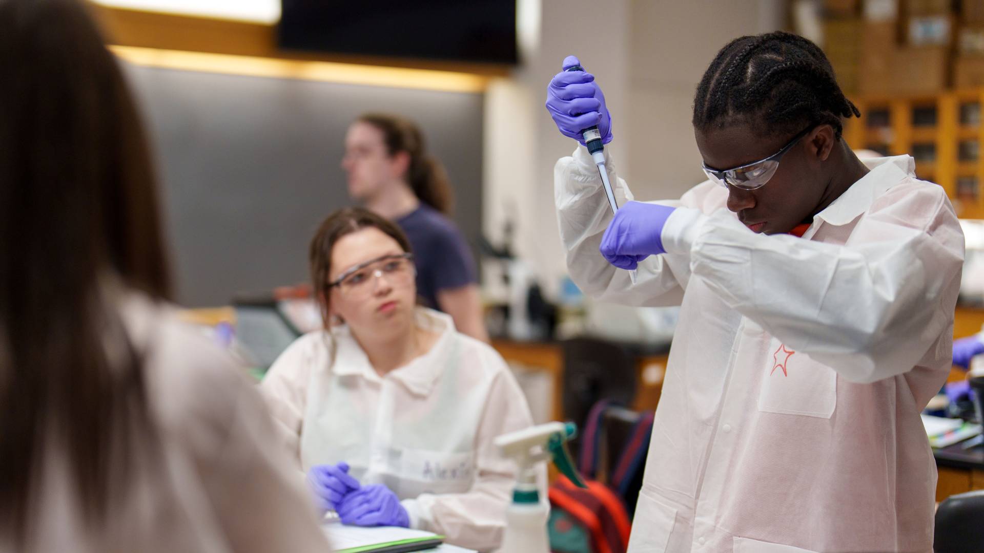 Students in a lab use pipettes in an activity
