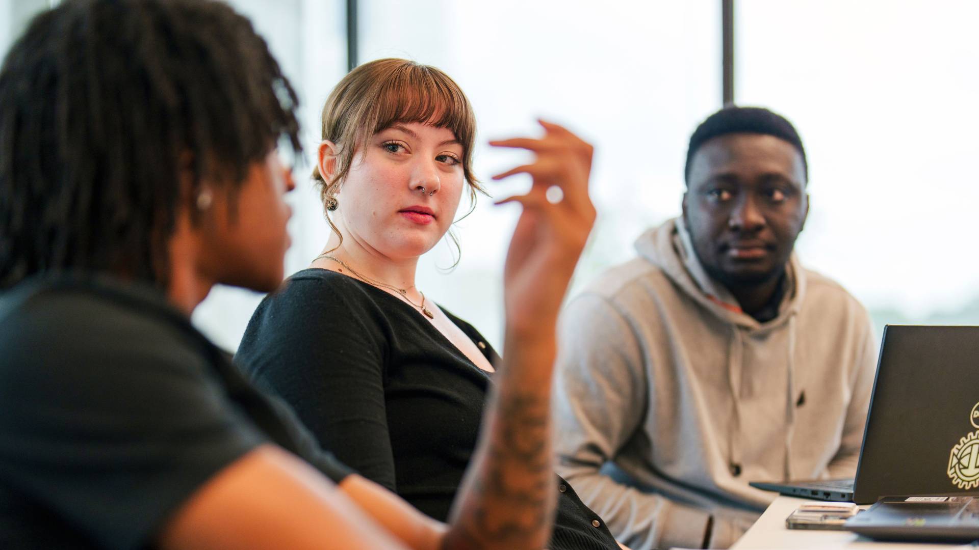 3 students engage in a discussion during a seminar