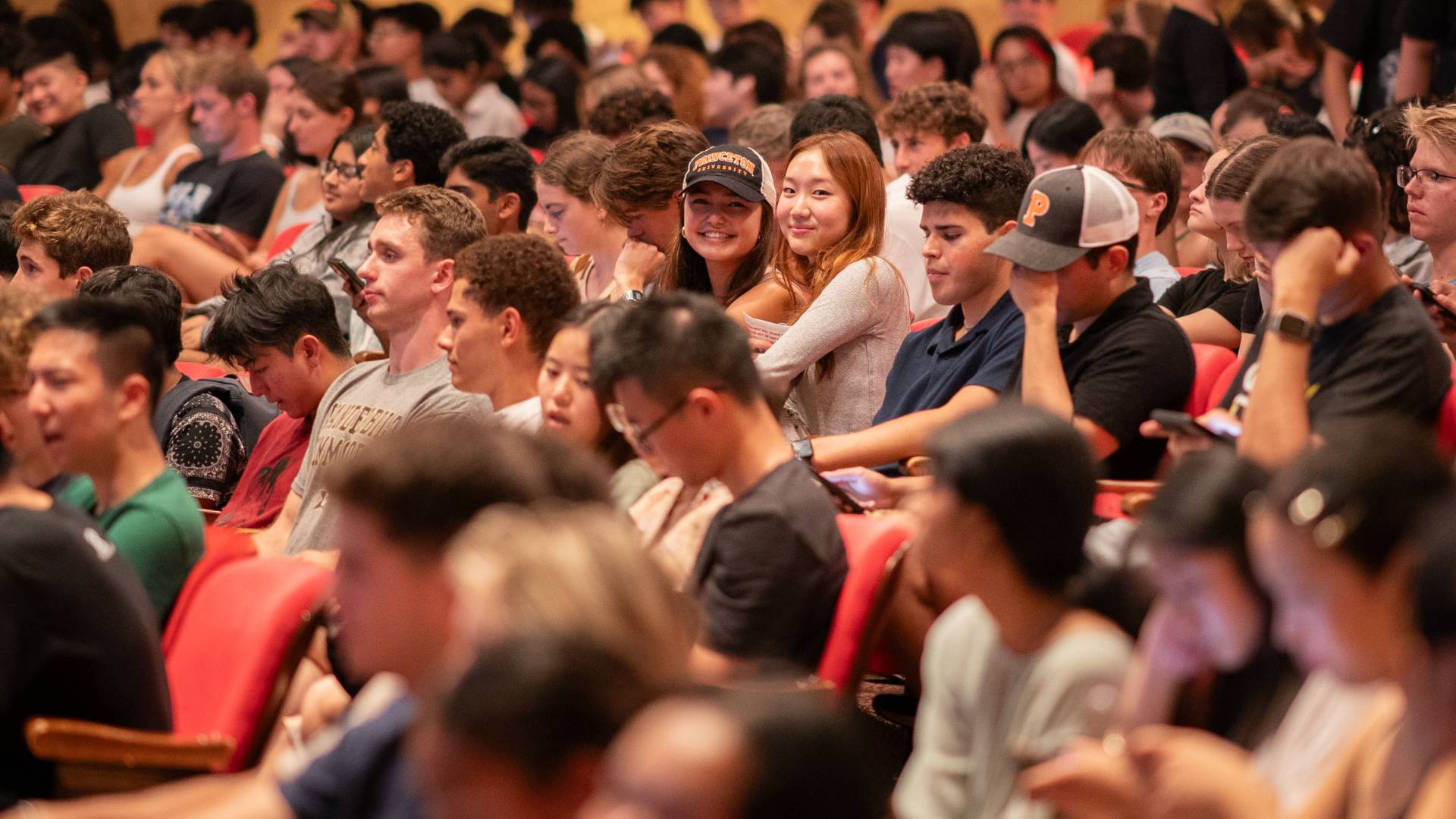 Students seated in the audience of the McCarter Theatre, smiling at the camera