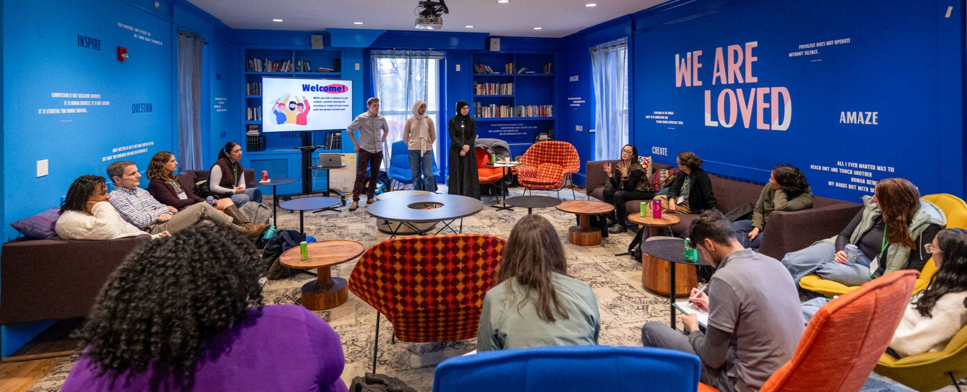 Students in a room with blue walls. Written on a wall: "You are loved."