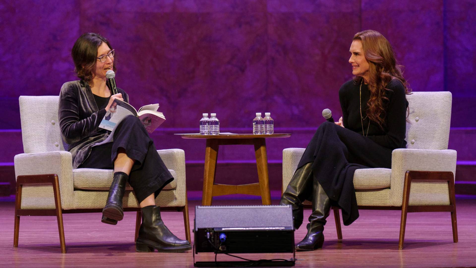 Brooke Shields in sitting on stage being interviewed by another person.