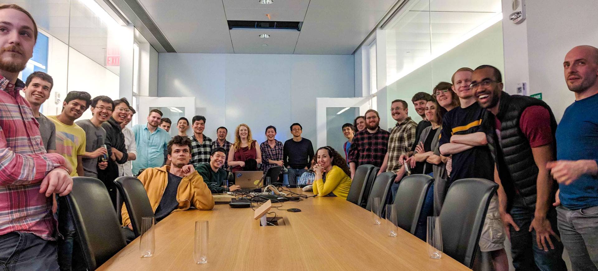 A crowd of young scientists gather around a table in a conference room.