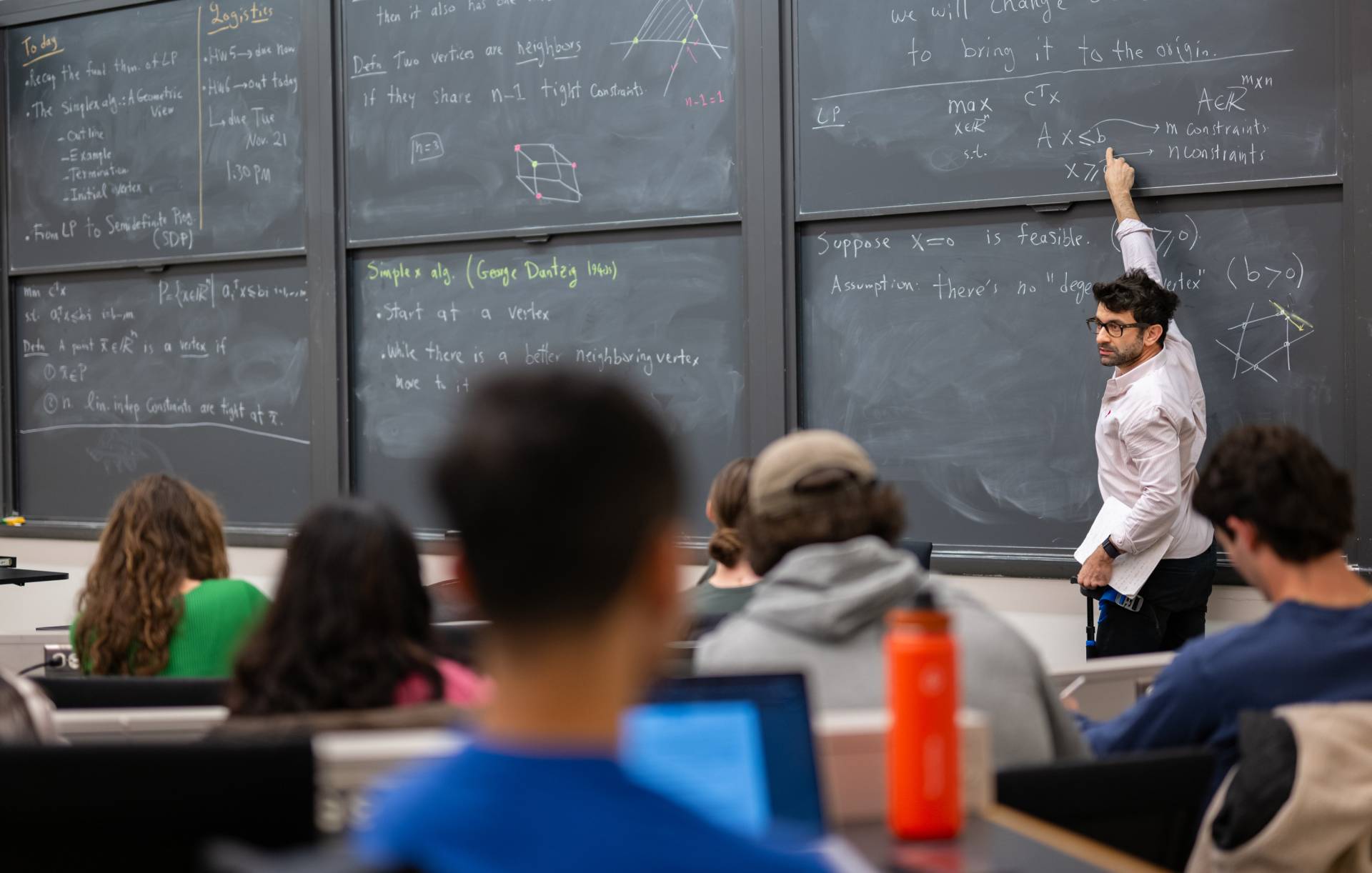Professor Amir Ali Ahmadi writes notes and calculations on a blackboard.