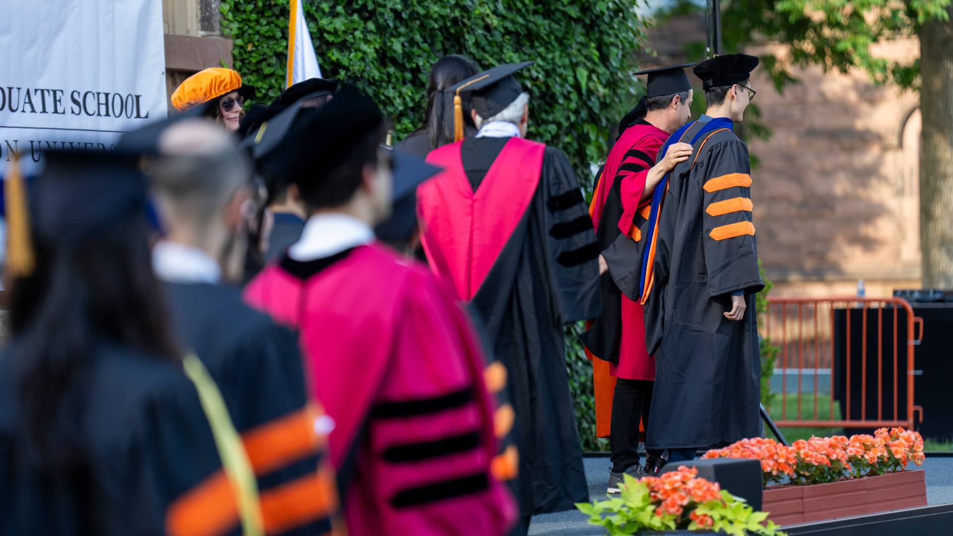 A line of people in colorful Ph.D. regalia.