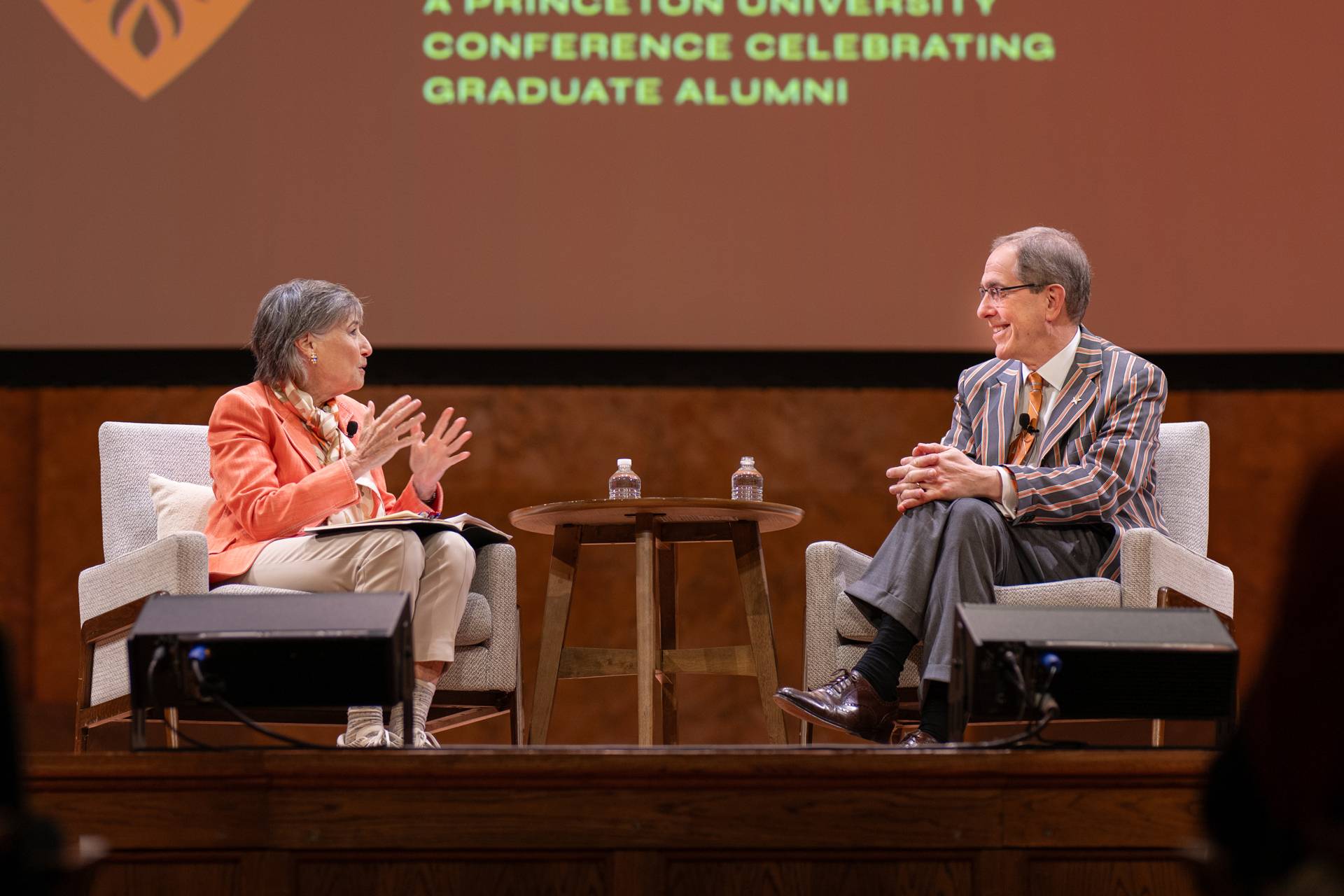 Seated on stage, conference co-chair Ann Kirschner and Christopher L. Eisgruber converse.
