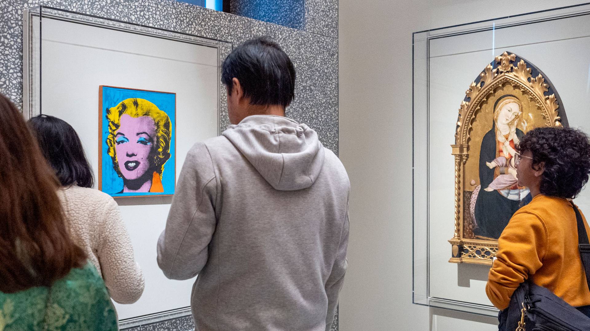 Two museum guests look at a display where a modern work is juxtaposed with a medieval one.