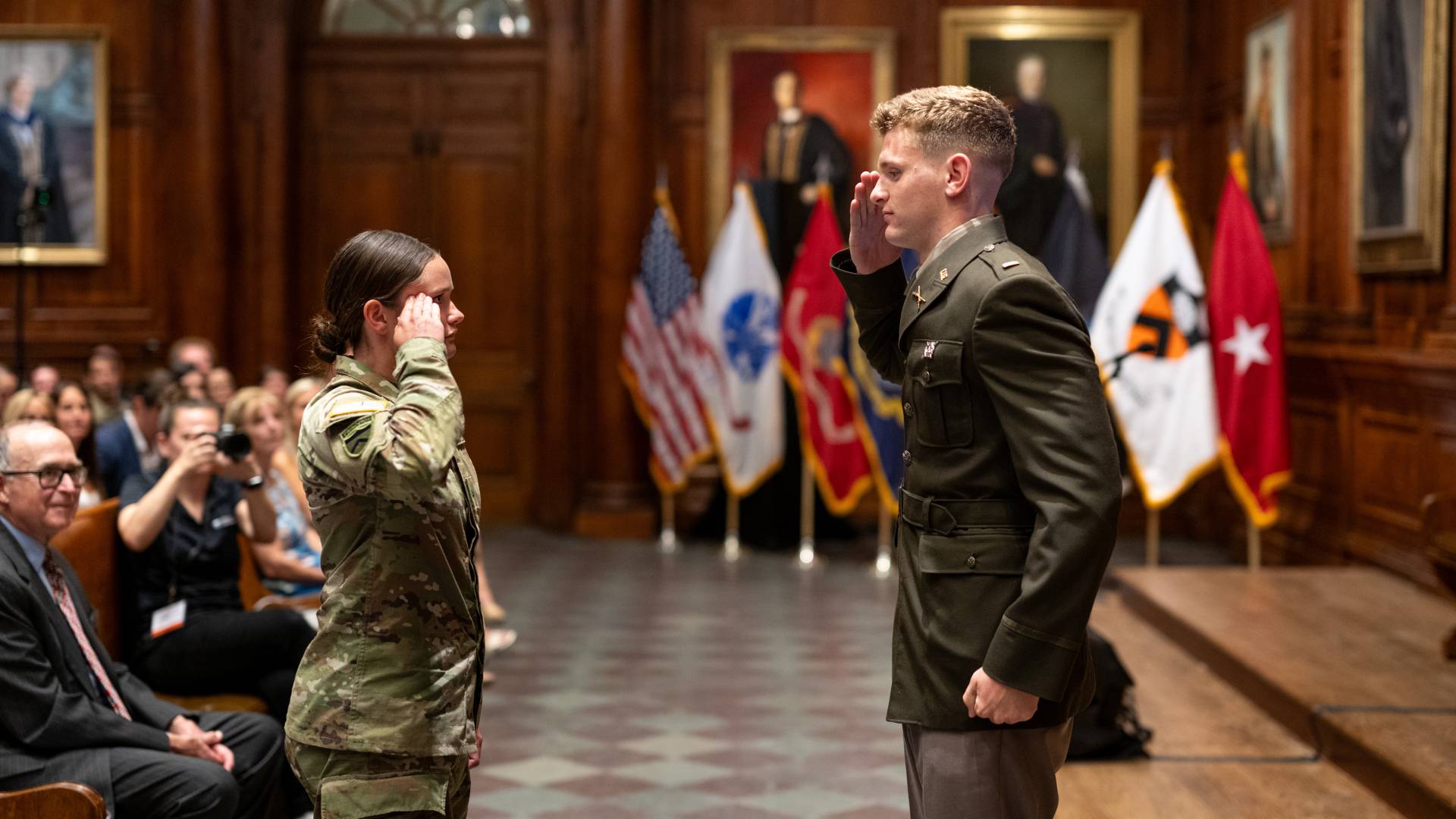 A commissioning officer stands opposite his younger sister as they salute each other