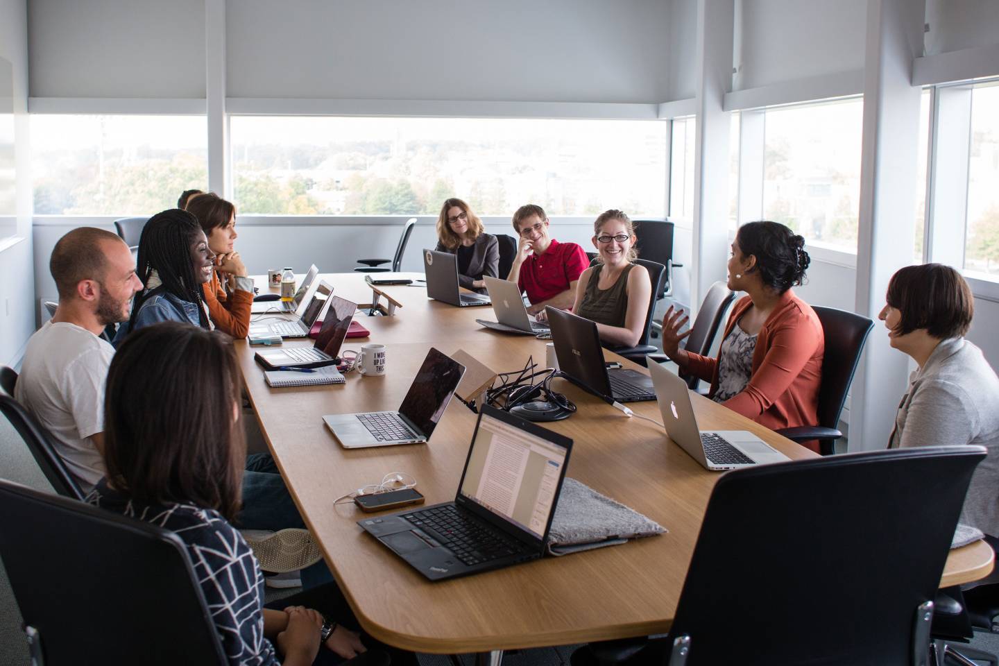 Graduate students sit around a table talking in a class