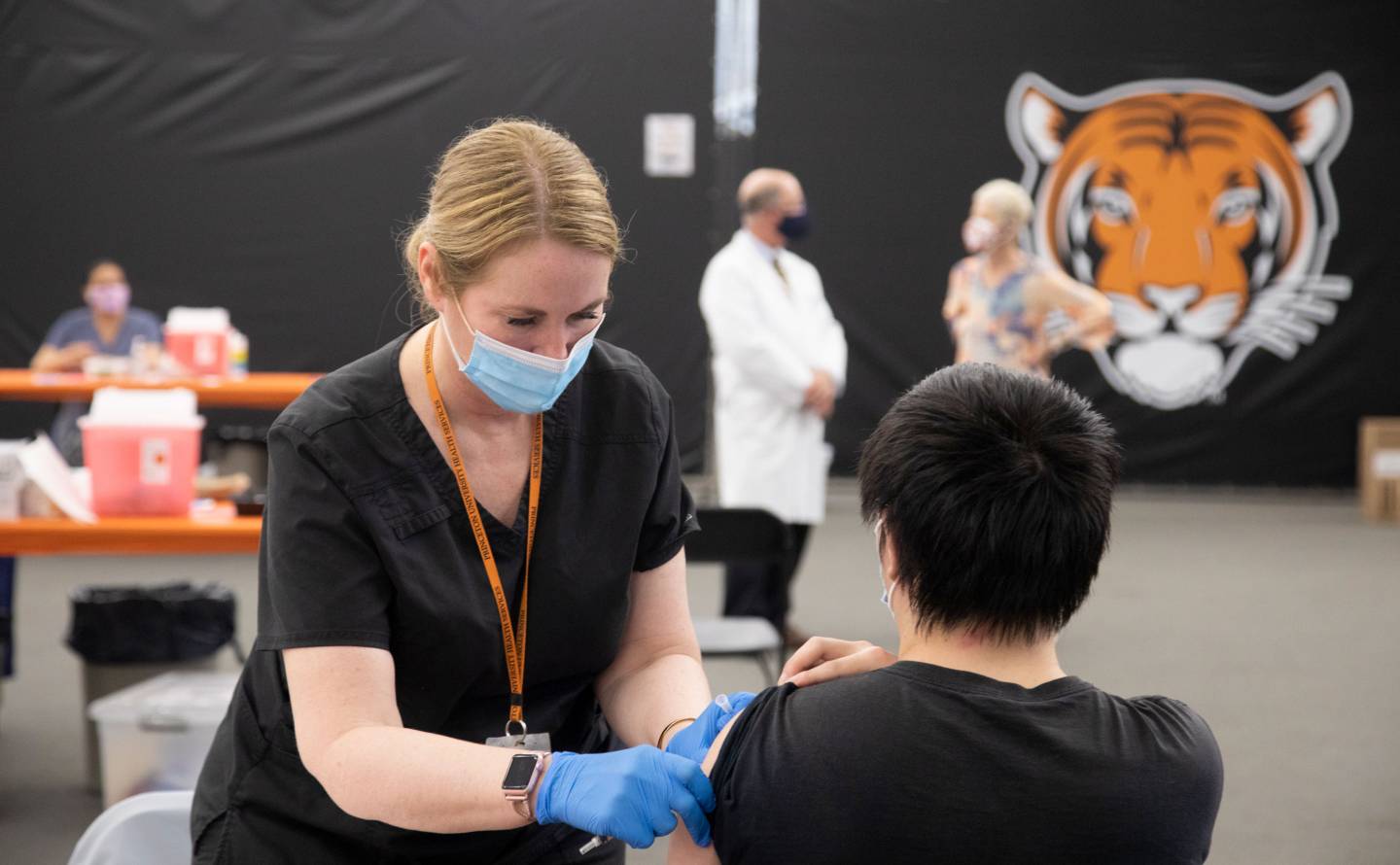 A nurse administers a vaccine to a student