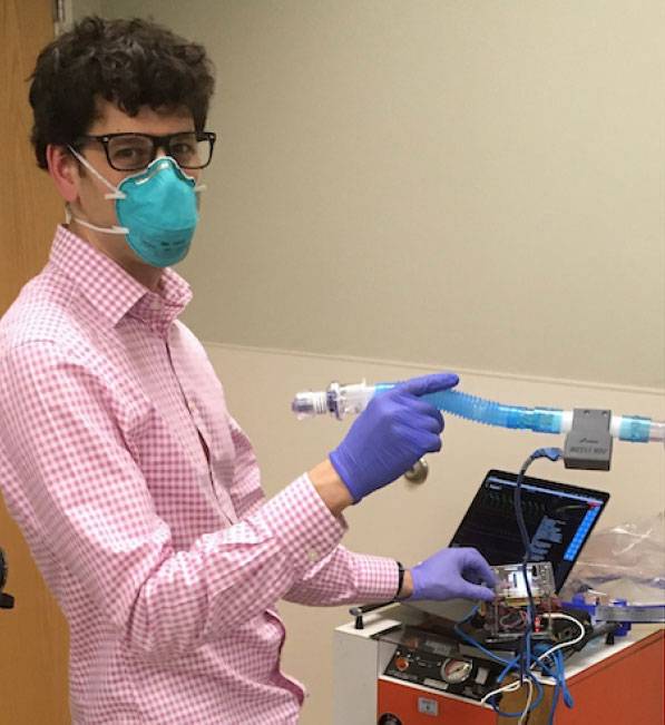 A person holding a tube and working with a laptop 