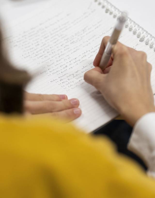 student hand writing notes on artificial intelligence language learning