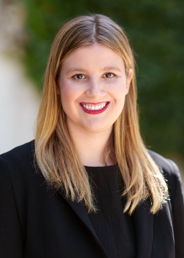 A smiling young woman with blond hair and a black blazer.