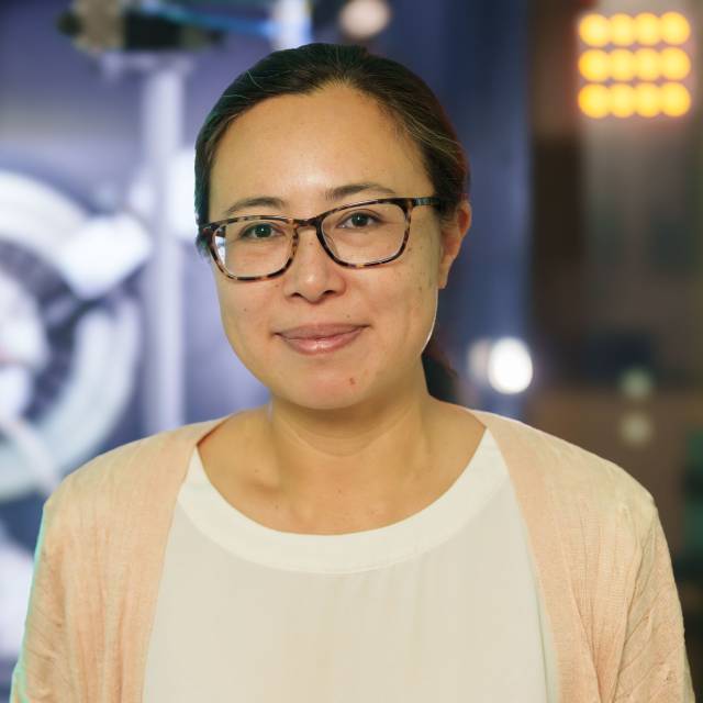 Nathalie de Leon smiles in glasses and a white shirt.